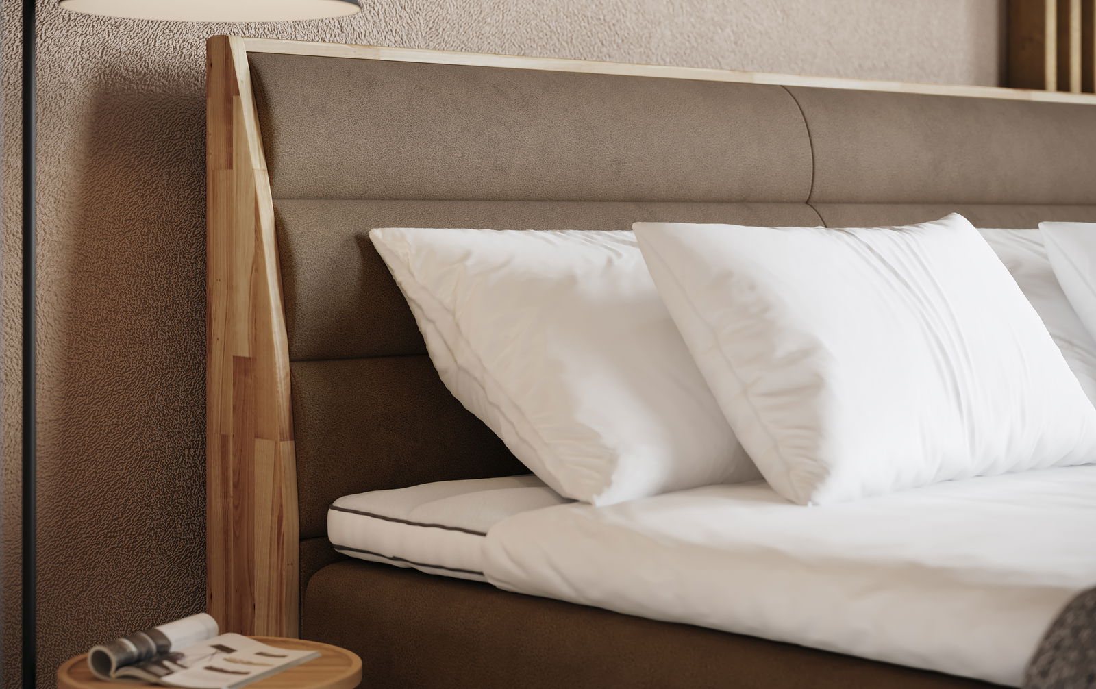 Nahaufnahme eines Boxspringbettes mit braunem Kopfteil und weißen Kissen, seitliche Perspektive