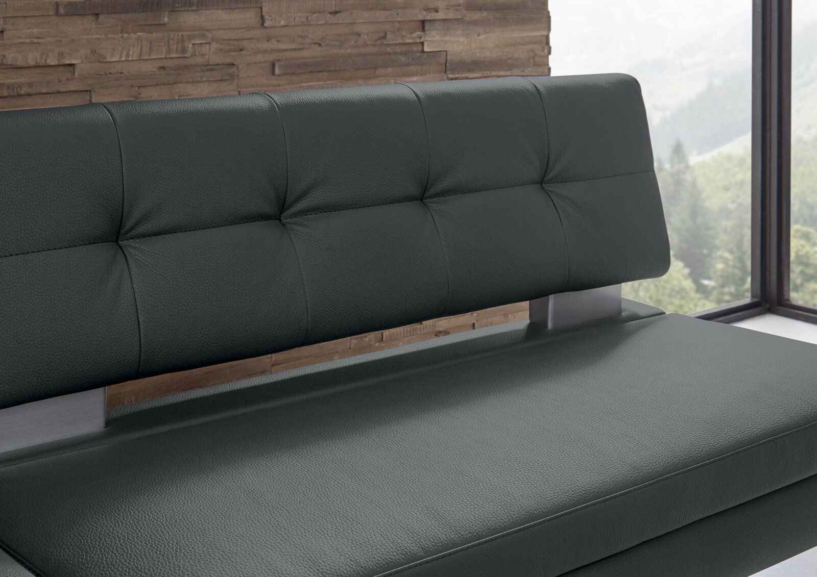 Nahaufnahme einer modernen Eckbank mit dunkelgrauem Lederbezug und gepolsterter Rückenlehne, seitliche Perspektive.