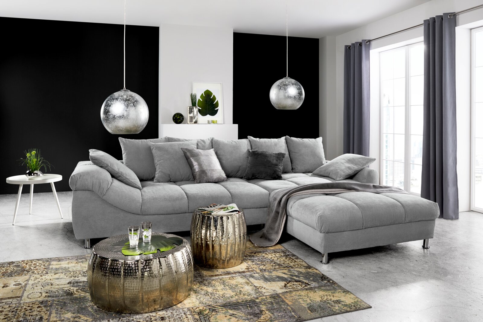 Graue Rundecke (L) in modernem Wohnzimmer, seitliche Perspektive, mit dekorativen Kissen und Decke, umgeben von stilvollen Möbeln und Accessoires.