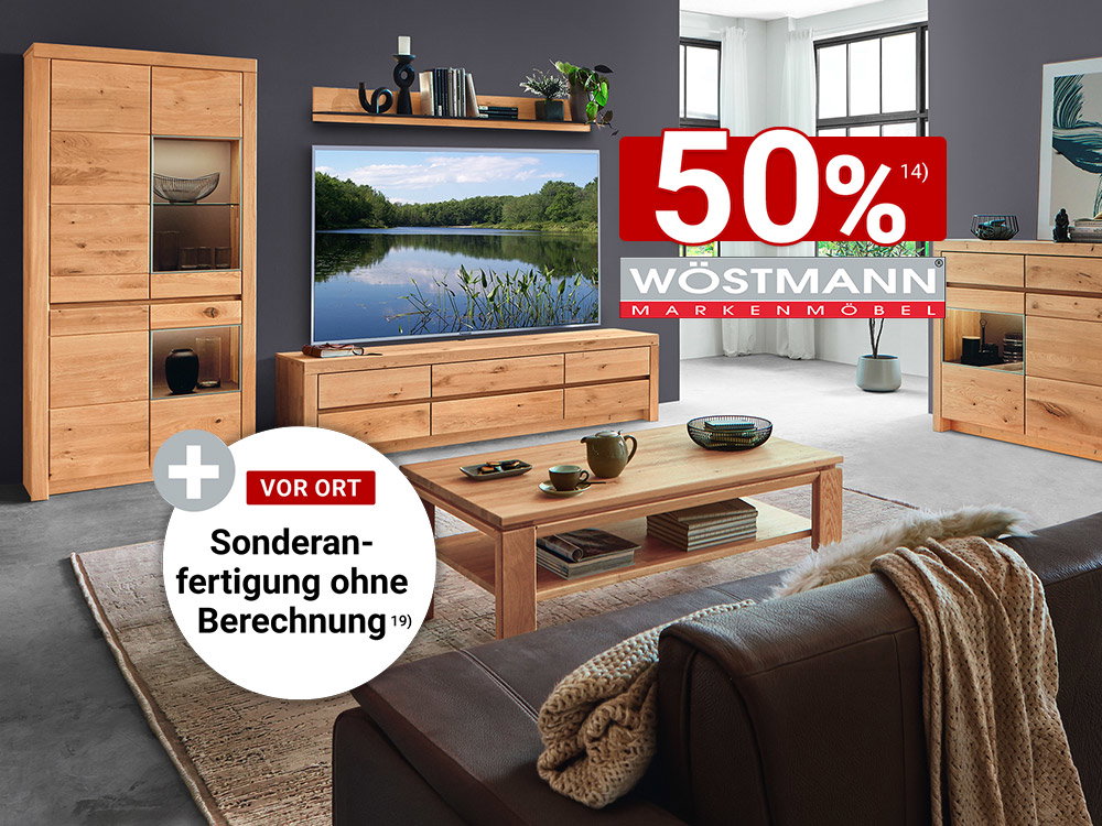 Modernes Wohnzimmer mit massiven Eichenmöbeln von Wöstmann, bestehend aus Vitrine, TV-Lowboard, Sideboard und Couchtisch vor dunkelgrauer Wandgestaltung.