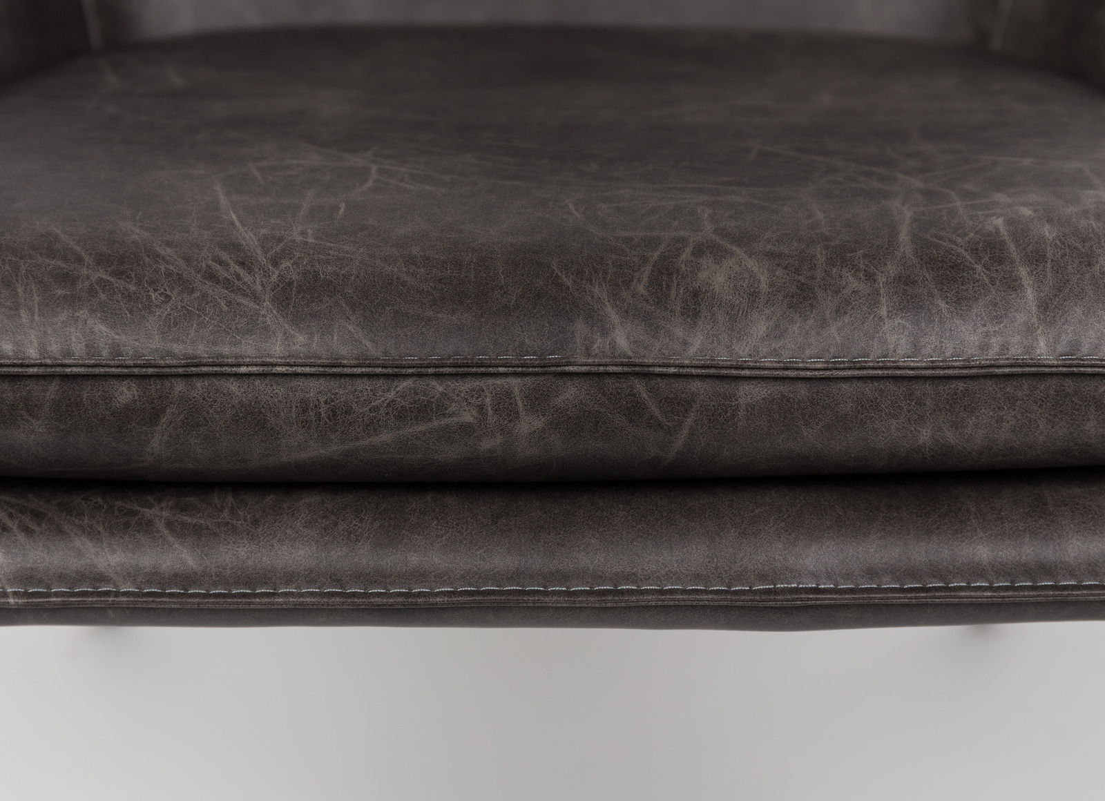 Nahaufnahme eines Sesselsitzes aus dunkelgrauem Leder mit sichtbaren Nähten, von vorne betrachtet.