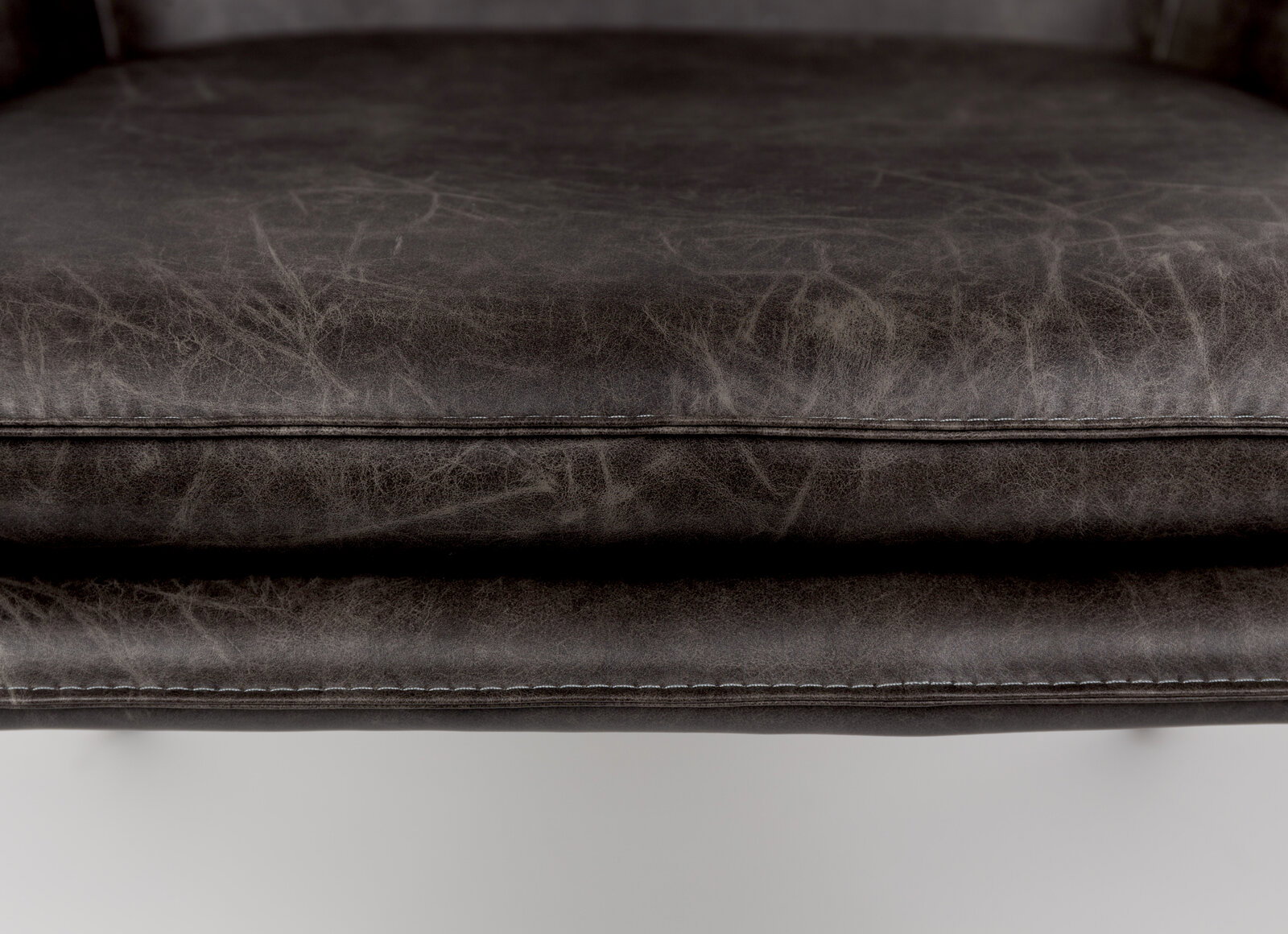 Nahaufnahme eines Sesselsitzes aus dunkelgrauem Leder mit sichtbaren Nähten, von vorne betrachtet.