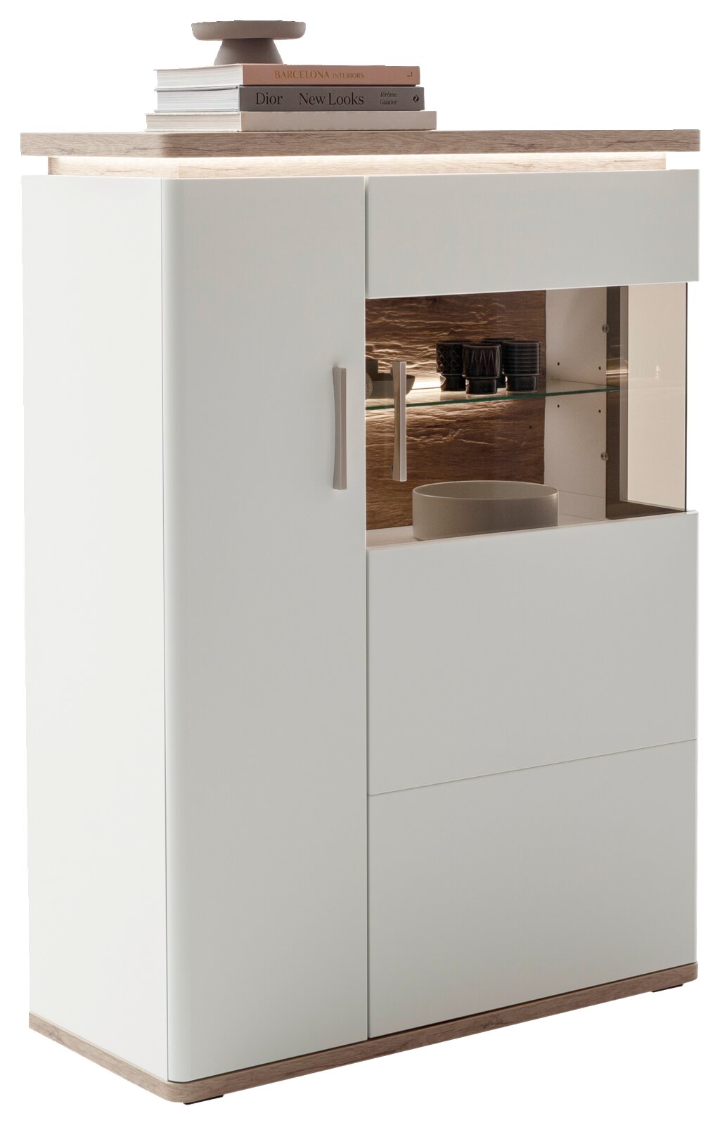 Moderne weiße Kommode/Highboard mit Holzoptik-Deckplatte und Sockel, links Tür mit Griff, rechts Vitrinenfach mit Glasboden und LED-Beleuchtung; Perspektive: frontale Ansicht leicht von links