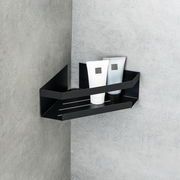 Schwarze Eckablage Meleto an einer grauen Wand montiert, mit zwei Tuben darauf, seitliche Perspektive.