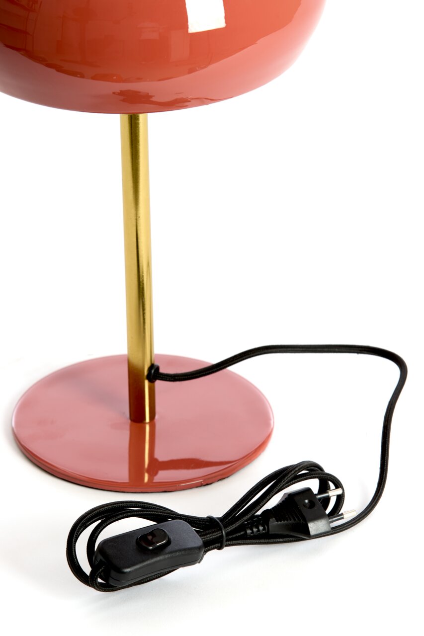 Nahaufnahme einer Tischleuchte mit rotem Lampenschirm und goldenem Ständer, inklusive schwarzem Kabel und Schalter.