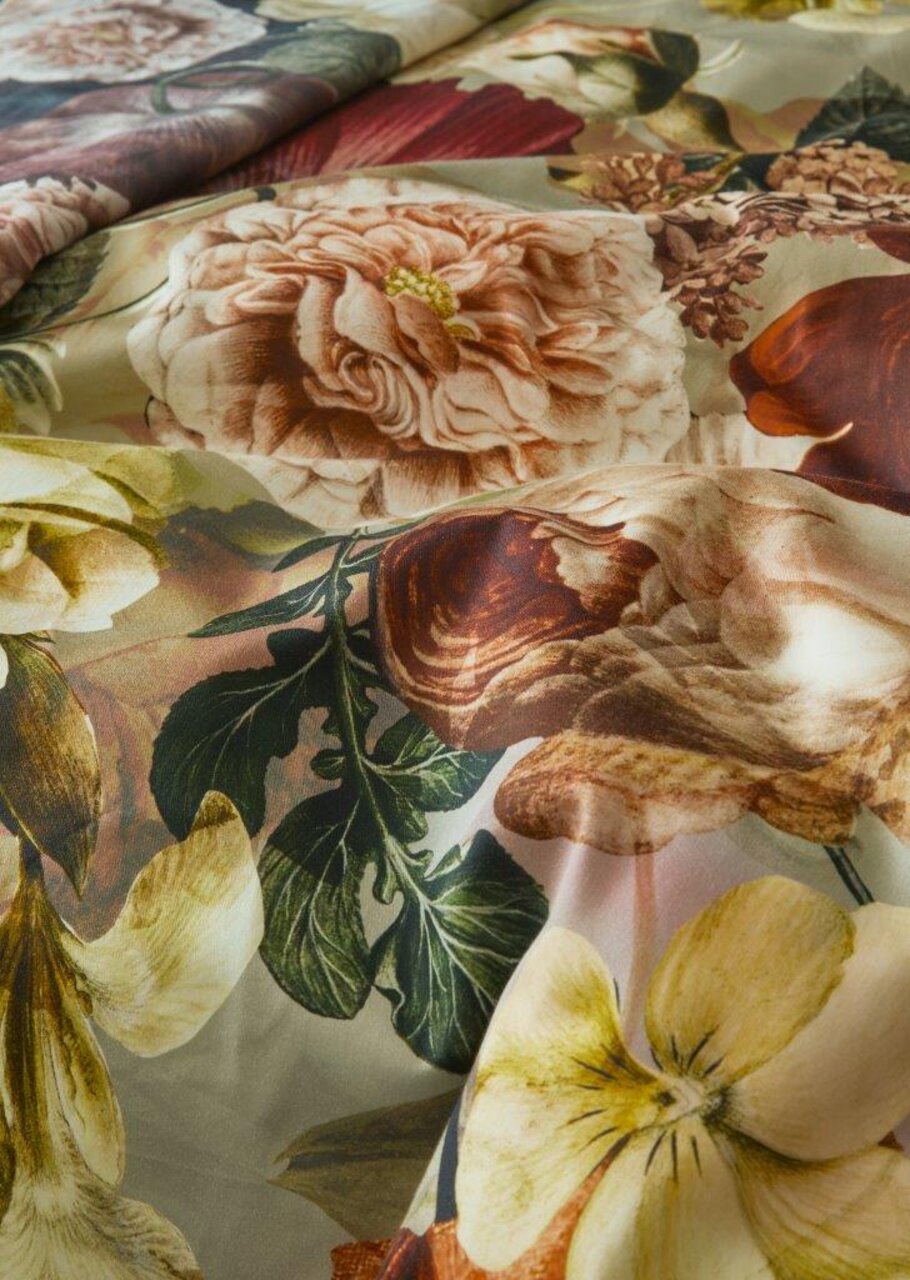 Nahaufnahme von Bettwäsche mit floralem Muster in warmen Farben, von oben betrachtet.