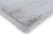 Nahaufnahme eines weichen, grauen Fellteppichs mit flauschiger Textur, perspektivisch von der Seite aufgenommen.