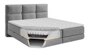 Graues Boxspringbett mit sichtbarem Querschnitt der Matratze, seitliche Perspektive