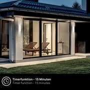 Moderne Akku-Außenwandleuchte an einem Haus bei Dämmerung, seitliche Perspektive