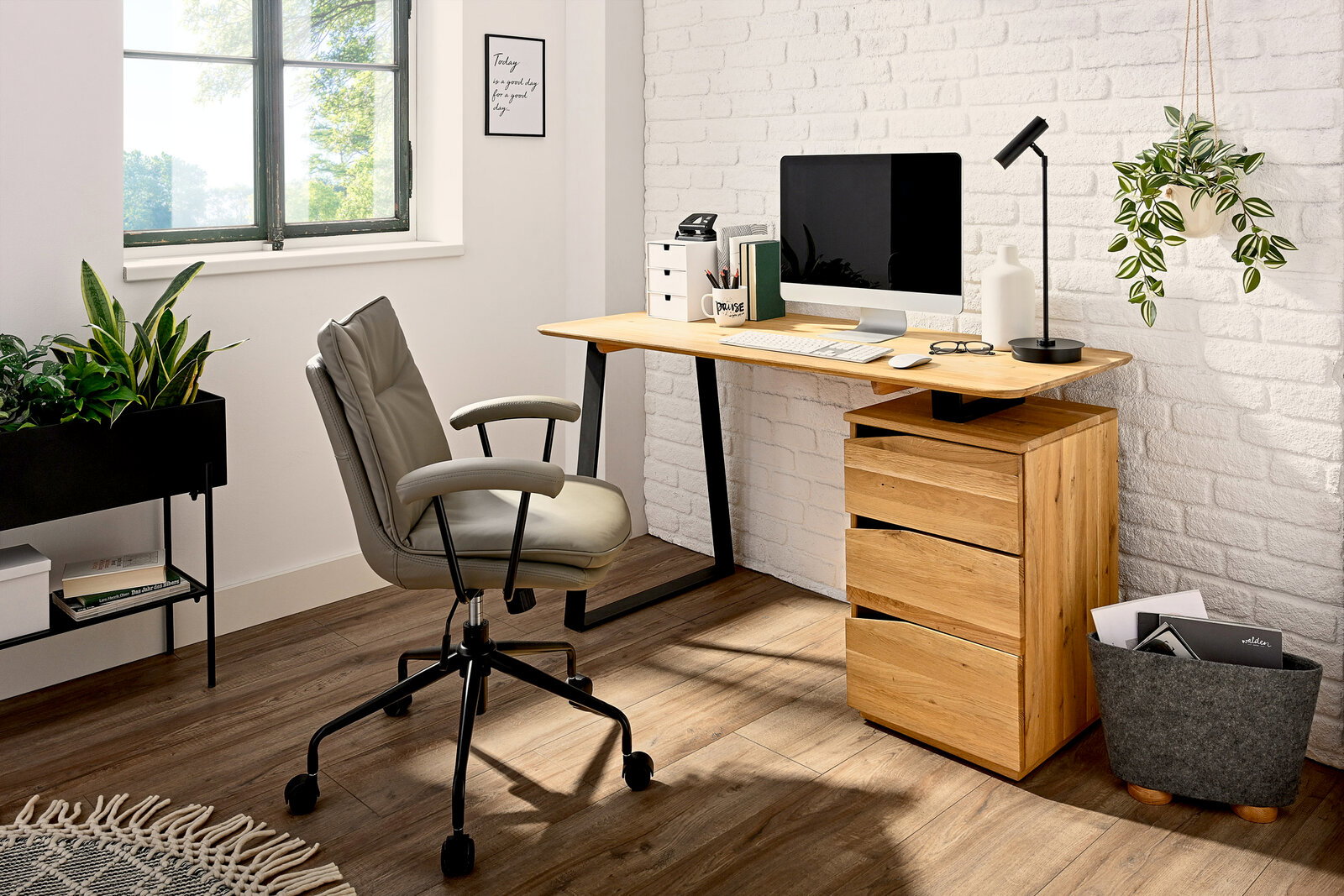 Moderner Schreibtisch mit Holzoberfläche und schwarzen Metallbeinen, ausgestattet mit einem Computer, Schreibtischlampe und Büromaterialien, seitliche Perspektive.