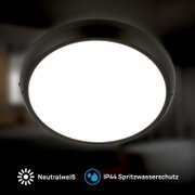 Ronde zwarte LED-plafondlamp met neutraalwit licht en IP44 spatwaterbescherming, frontaal van voren gefotografeerd.