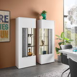 Zwei moderne Highboards in Weiß mit Glaseinsätzen, dekoriert mit Vasen und Geschirr, in einem stilvollen Wohnzimmer mit oranger Wand und großem Fenster, seitliche Perspektive.