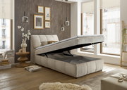 Boxspringbett mit hochgeklappter Matratze, seitliche Perspektive, modernes Schlafzimmerdesign mit großen Fenstern und stilvollen Dekorationen.