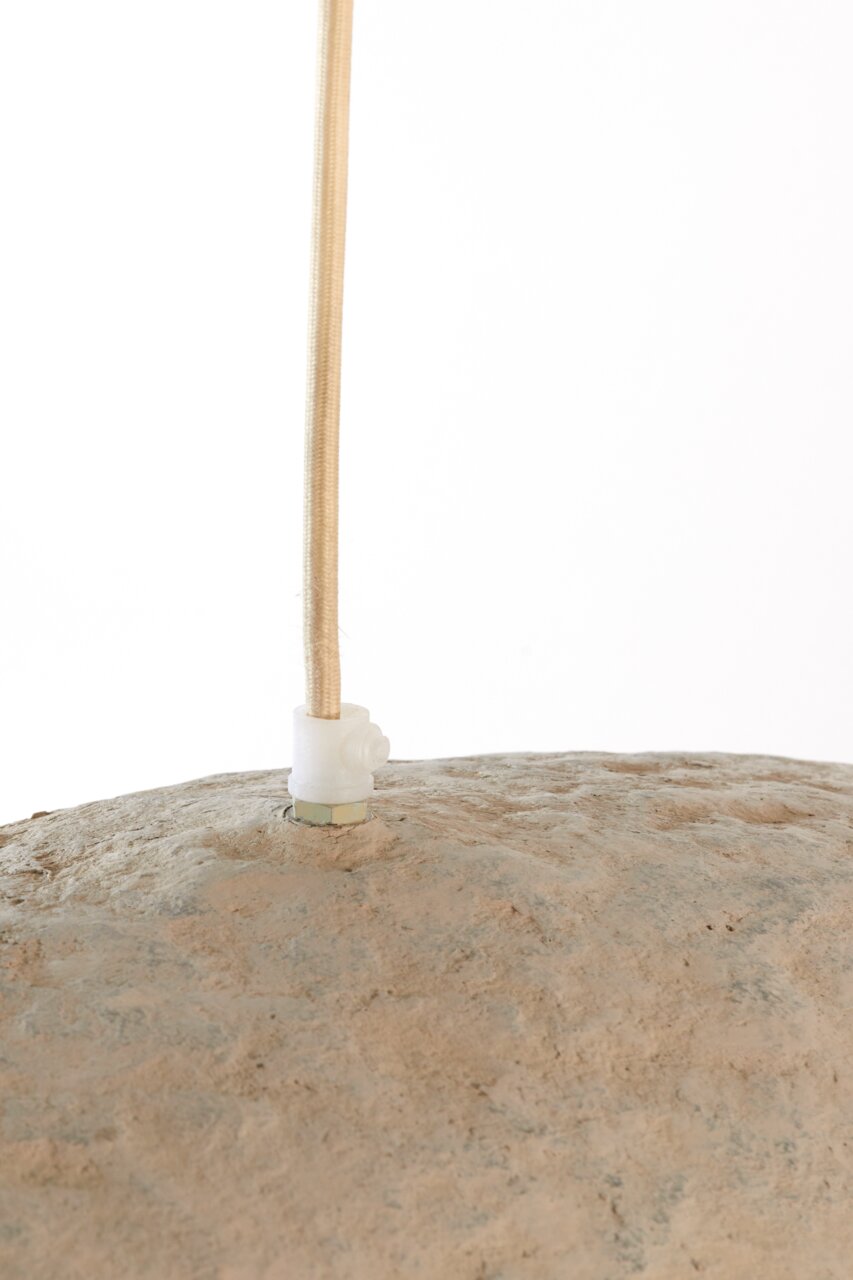 Nahaufnahme einer Hängeleuchte mit natürlicher, steinartiger Oberfläche und einem beige ummantelten Kabel von oben.