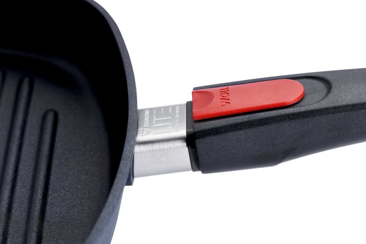 Nahaufnahme einer Guss-Steakpfanne mit rotem Griffdetail, seitliche Perspektive