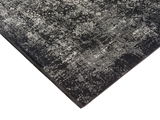 Designer Teppich in Schwarz und Grau mit komplexem Muster, perspektivisch von der Ecke aufgenommen