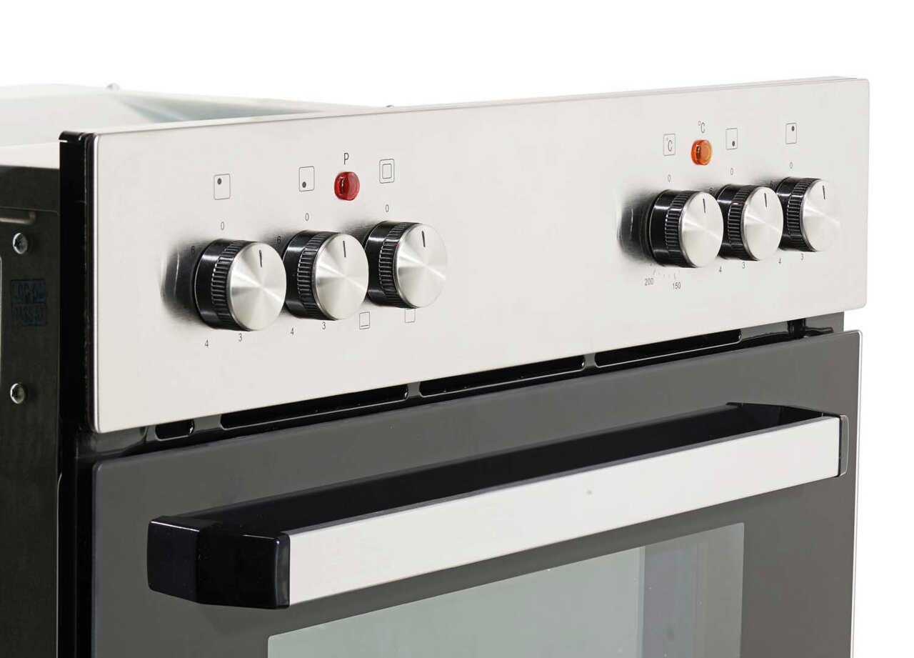 Close-up van een moderne oven met zilveren draaiknoppen en een zwarte handgreep, gezien vanaf de zijkant