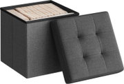 Graue, gepolsterte Aufbewahrungsbox/Sitzhocker aus Stoff mit abgenommenem Deckel, oben mit Decken gefüllt; Produktansicht in schräger Perspektive von vorne/oben.