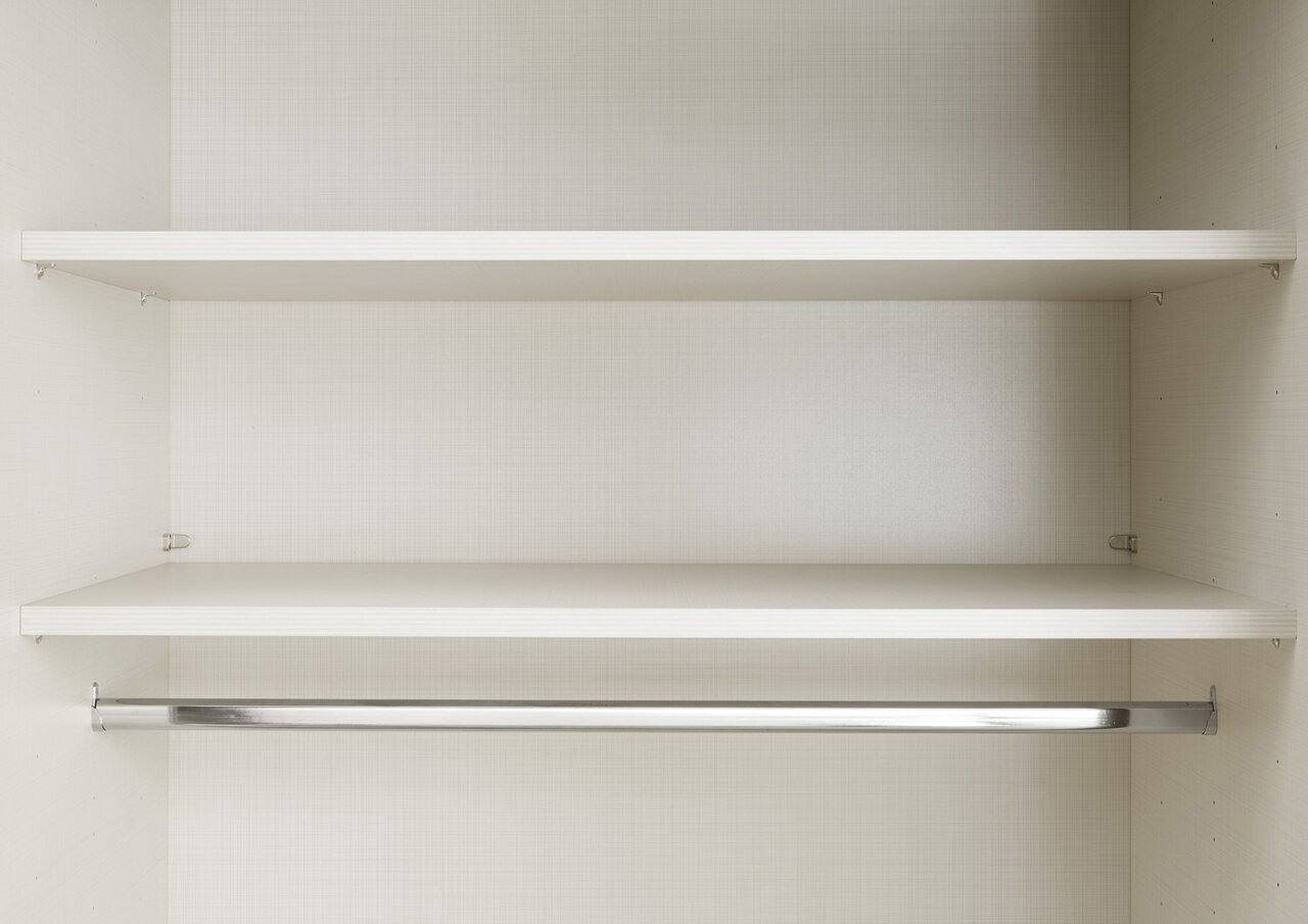 Innenansicht eines Schwebetürenschranks mit zwei Regalböden und einer Kleiderstange, frontal betrachtet.