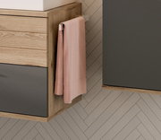 Handtuchhalter an einem Holzschrank montiert, mit einem rosa Handtuch, seitliche Perspektive