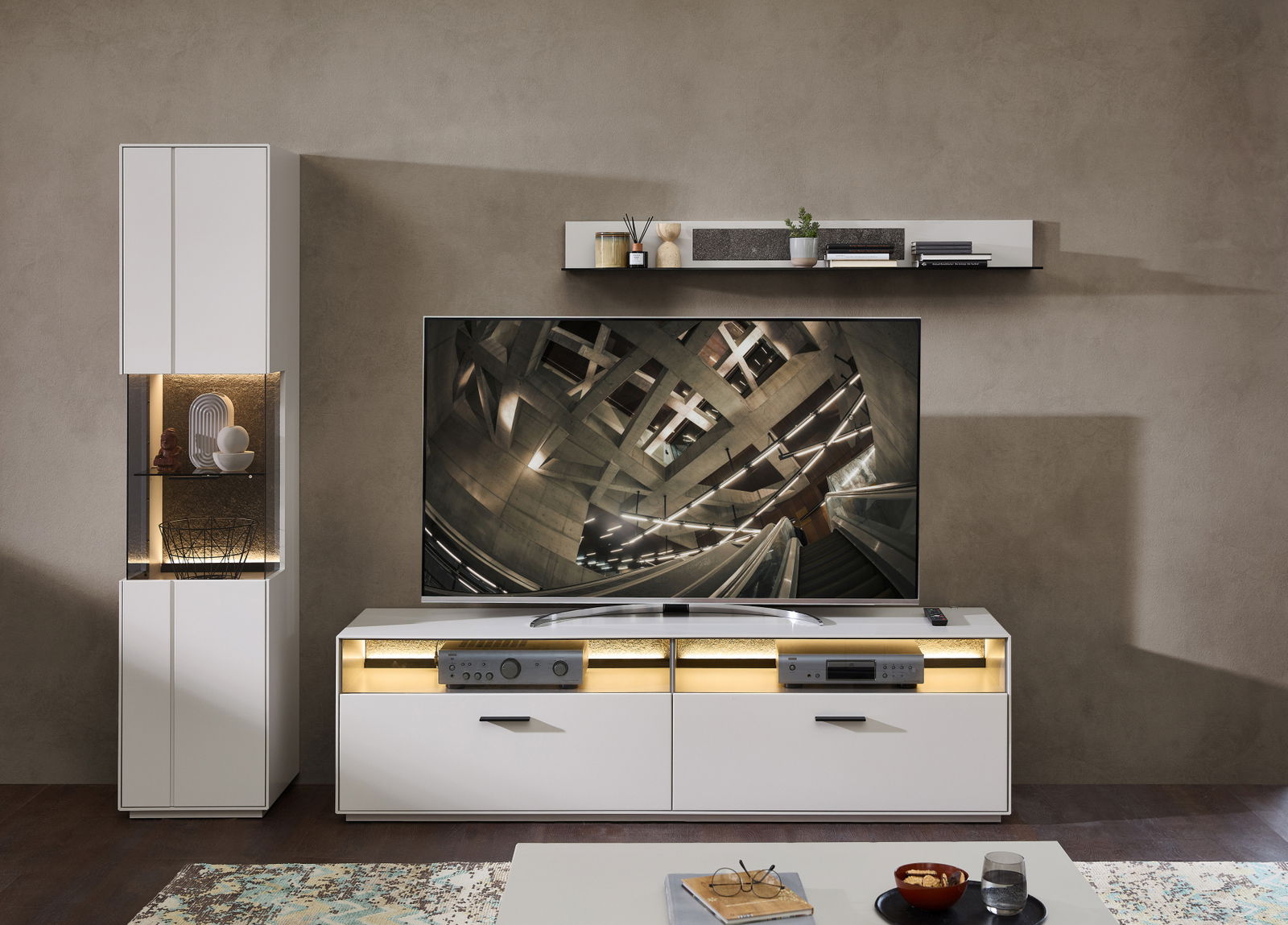 Modernes Wohnzimmer mit Wandboard in Weiß, dekoriert mit Pflanzen und Büchern, aus der Frontalperspektive.