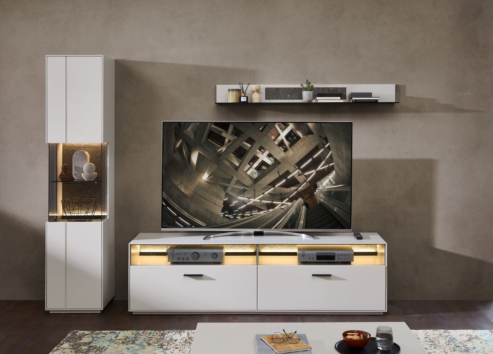 Modernes Wohnzimmer mit Wandboard in Weiß, dekoriert mit Pflanzen und Büchern, aus der Frontalperspektive.