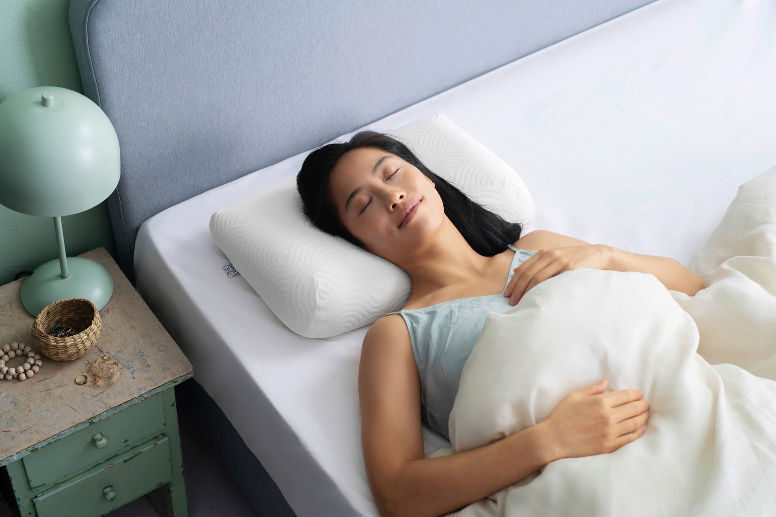 Frau schläft friedlich auf einem weißen Schlafkissen in einem Bett, seitliche Perspektive