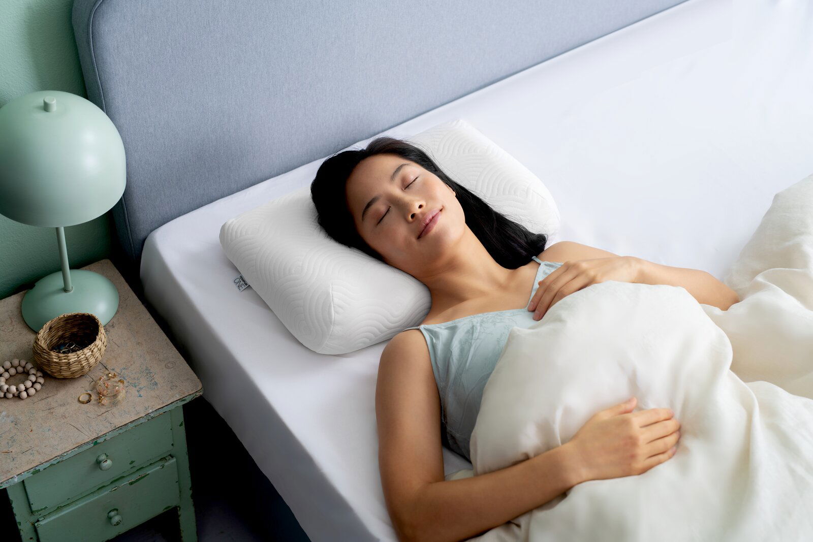 Frau schläft friedlich auf einem weißen Schlafkissen in einem Bett, seitliche Perspektive