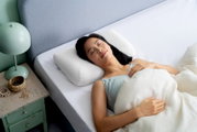 Een vrouw slaapt vredig op een wit kussen in een bed, gezien vanuit een zijaanzicht