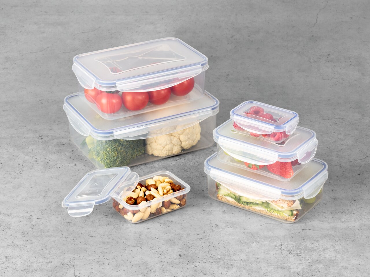 Frischhaltedosen-Set aus Kunststoff, gefüllt mit verschiedenen Lebensmitteln, aus leicht erhöhter Perspektive fotografiert.