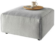 Grauer Hocker mit gerippter Oberfläche, darauf ein Tablett mit Tasse und Besteck, seitliche Perspektive