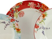 Drei dekorative Porzellanteller mit floralen Motiven und farbigen Rändern (rot und hellblau) in Nahaufnahme, Draufsicht auf die Telleroberseiten.