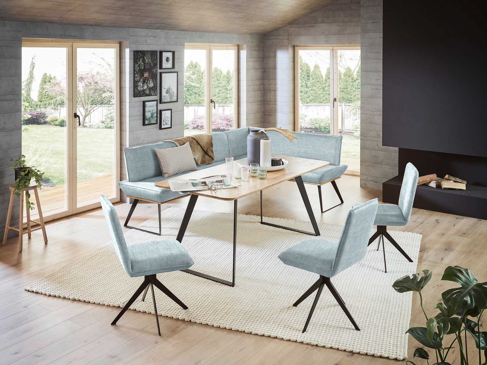 Voleo Hoekbank 243 x 183 cm MALIBU Moderne Eckbank 243x183 cm in einem hellen Raum mit großen Fenstern, umgeben von stilvollen Stühlen und einem Holztisch, aus der Perspektive des Raumes betrachtet.