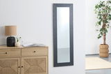 Rechteckiger Wandspiegel mit dunklem, strukturiertem Rahmen, aufgehängt in einem modernen Raum mit Kommode, Lampe und Pflanze, seitliche Perspektive.