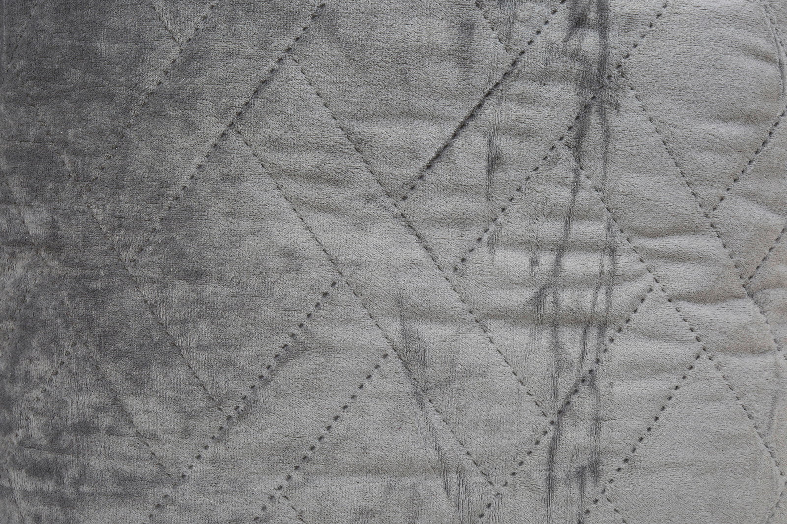 Nahaufnahme einer grauen Tagesdecke mit gestepptem Rautenmuster.