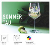 Weinglas mit floralem Design, gefüllt mit Getränk und Limettenscheiben, auf grünem Hintergrund, seitliche Perspektive