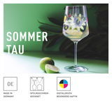 Weinglas mit floralem Design, gefüllt mit Getränk und Limettenscheiben, auf grünem Hintergrund, seitliche Perspektive