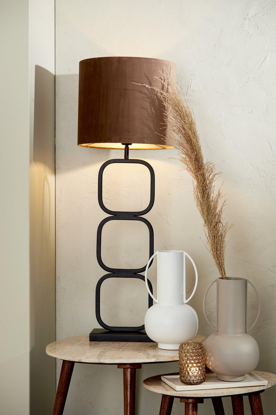 Light&Living Schaal MAES Moderne tafellamp met bruine kap en geometrische metalen voet, gezien vanaf de zijkant, op een tafel met twee decoratieve vazen en een theelichthouder.