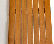 Nahaufnahme einer Gartenlounge mit Holzlatten und einem hellen Kissen, von oben betrachtet.