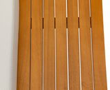 Nahaufnahme einer Gartenlounge mit Holzlatten und einem hellen Kissen, von oben betrachtet.