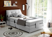 Graues Boxspringbett in modernem Schlafzimmer, seitliche Perspektive, mit Dekoration und Tageslicht.