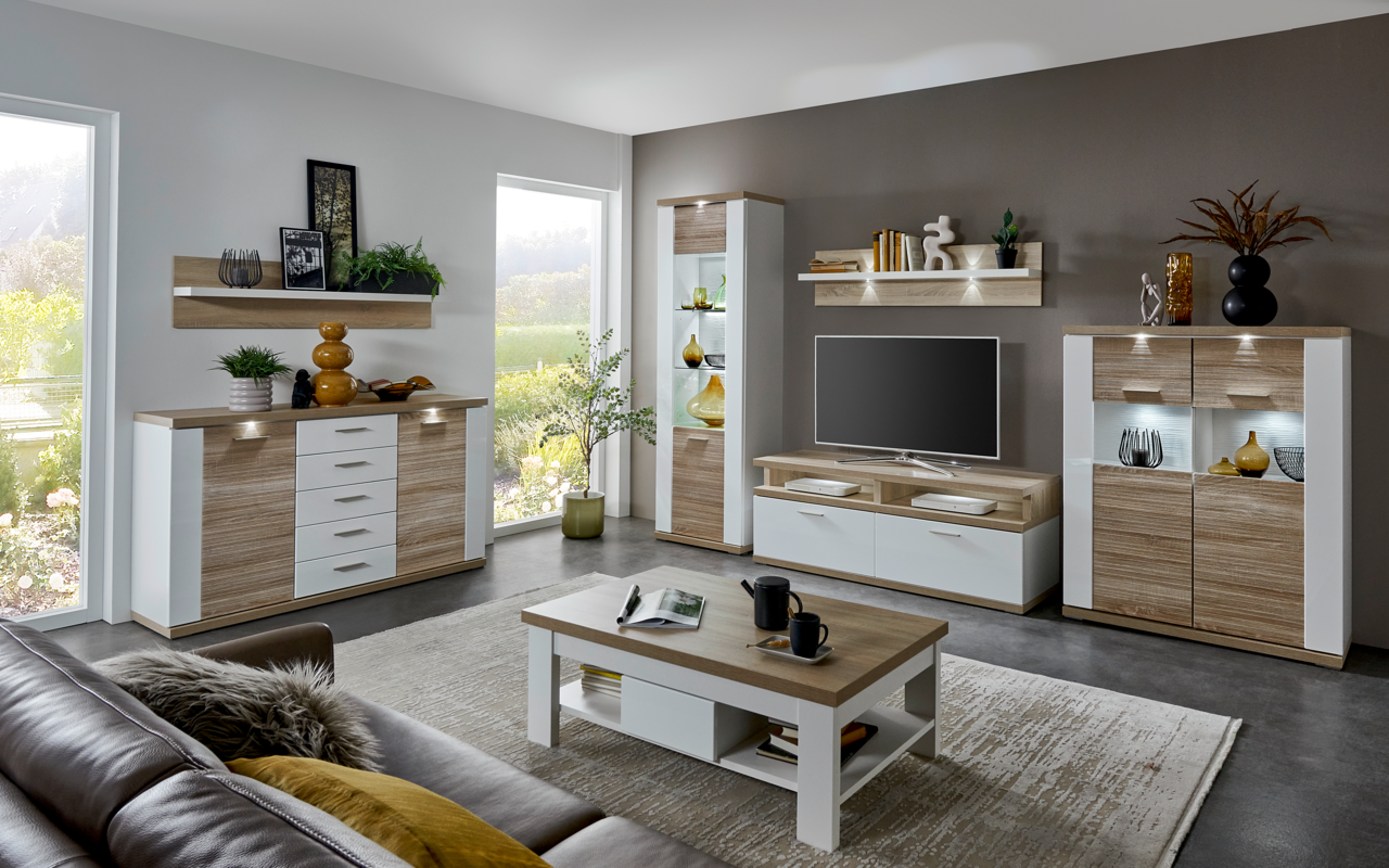 XORA Couchtisch MANHATTAN Moderner Couchtisch in Holzoptik mit weißem Gestell, zentral im Wohnzimmer platziert, umgeben von stilvollen Möbeln und Dekorationen, aus der Perspektive eines Sitzenden auf dem Sofa.