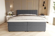 Gepolstertes Boxspringbett in dunkelgrauem Stoff mit gepolstertem Kopfteil und weißer Bettwäsche, frontal aus leicht erhöhter Perspektive im modernen Schlafzimmer