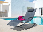 Moderne Schaukelliege aus Metall und Stoff, seitliche Perspektive, auf einer Terrasse neben einem Pool, mit einem pinken Handtuch.