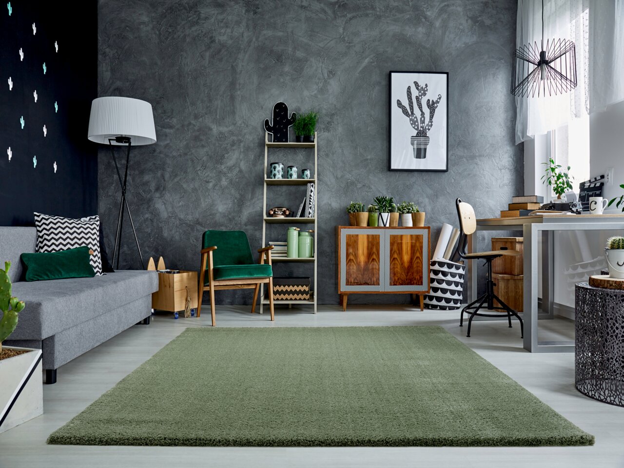 Grüner Teppich Soft Dream ca. 240x290cm in modernem Wohnzimmer mit grauer Couch, grünen Akzenten und Pflanzen, aus der Perspektive des Raumes betrachtet.