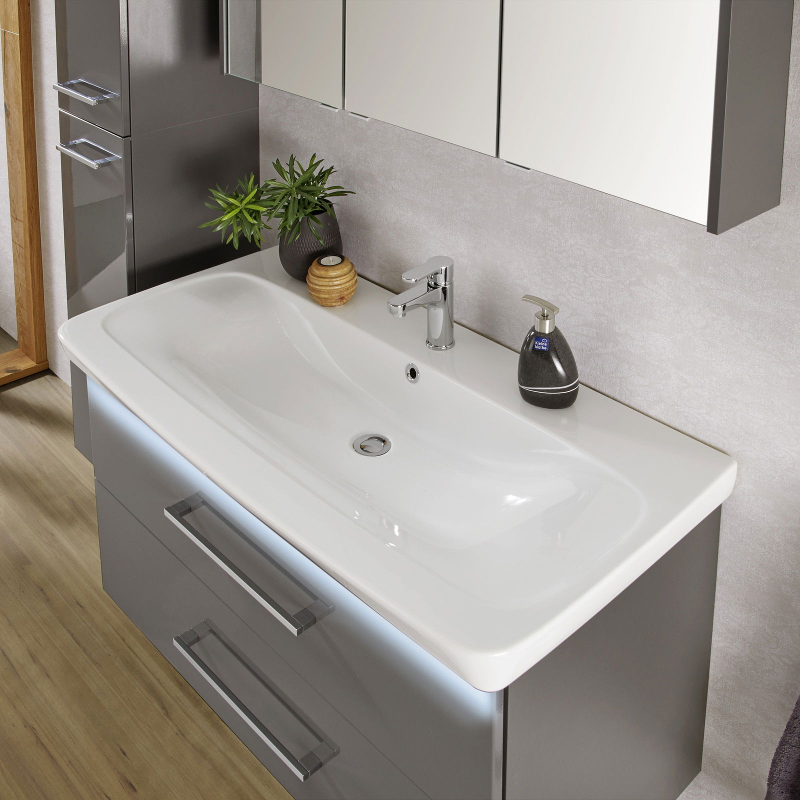 Moderner Waschtisch mit glänzendem Wasserhahn, dekorativen Pflanzen und Seifenspender, aus der Vogelperspektive fotografiert.