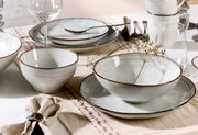 Elegantes Tafelset mit acht Teilen, bestehend aus Tellern, Schalen und Gläsern, auf einem gedeckten Tisch von schräg oben fotografiert.
