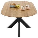Esstisch mit ovaler Holzplatte und schwarzem Metallgestell, von oben betrachtet, dekoriert mit einem Obstkorb und zwei Tassen.