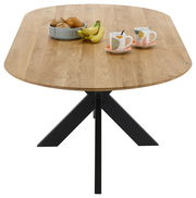 Esstisch mit ovaler Holzplatte und schwarzem Metallgestell, von oben betrachtet, dekoriert mit einem Obstkorb und zwei Tassen.