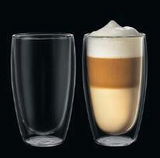 Zwei Latte Macchiato Gläser, eines leer und eines gefüllt, aus seitlicher Perspektive